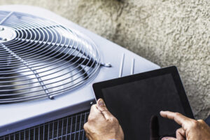 Don't Skip Your Annual Furnace Inspection. Maintenance engineer using digital tablet to inspect air conditioning unit.