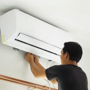 Video - 4 Amazing Benefits of Ductless Units. Image shows HVAC professional working on a ductless mini split on home interior.